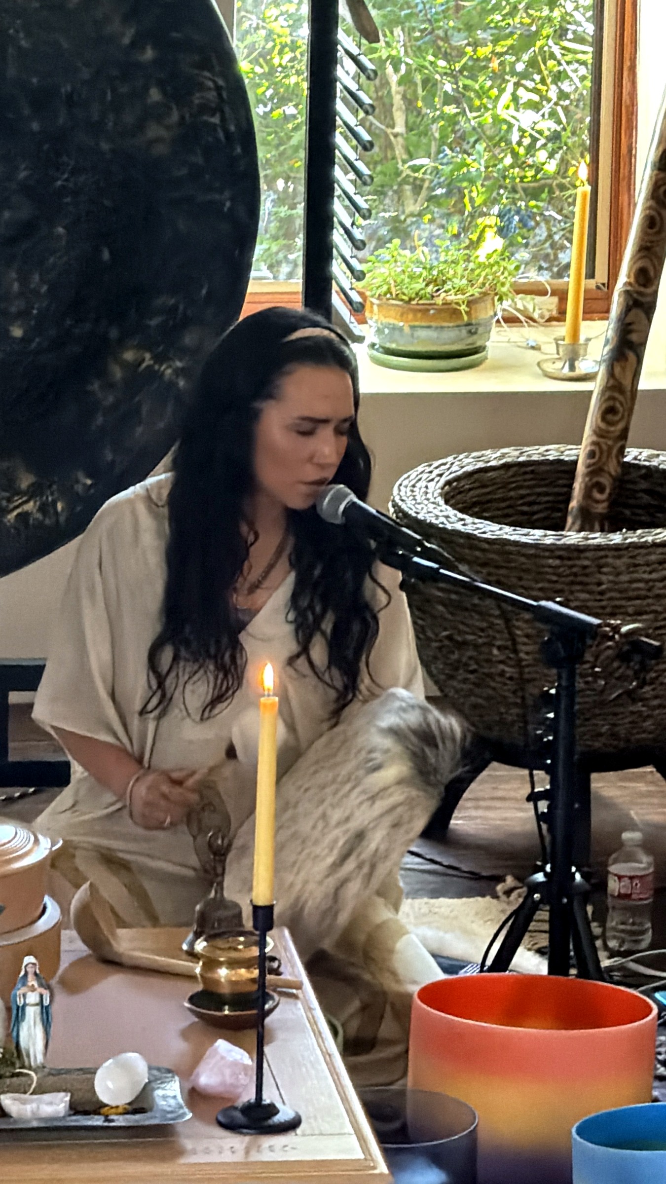 Letty singing beside a candle, gong, crystal bowls, and incense