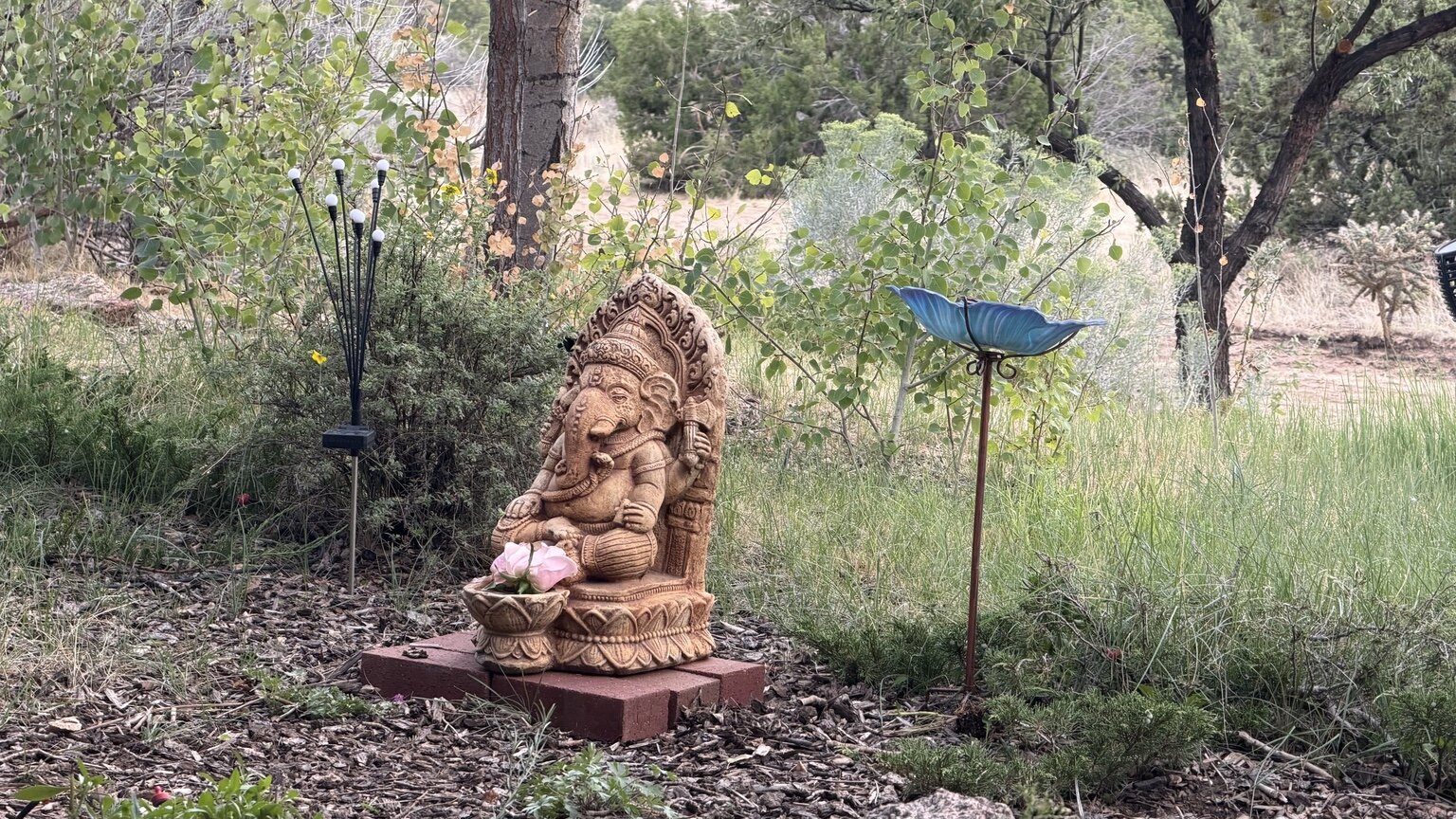 A Ganesha figure with flowers in a garden at Rancho Los Dragones Dorados
